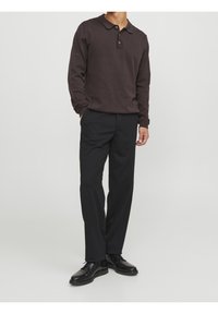 Polo de manga larga marrón oscuro con cuello y tres botones, combinado con pantalones negros y zapatos negros, con un diseño de corte recto.