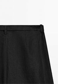 Pantalon noir ajusté avec passants de ceinture et couture avant nette, présenté de la taille à mi-cuisse sur fond blanc uni.