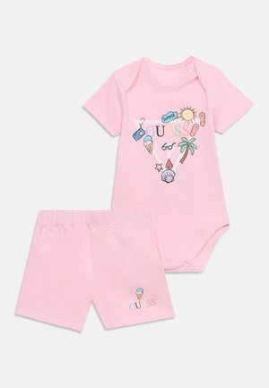 Conjunto de pelele de manga corta y pantalones cortos para bebé en color rosa con estampados de temática veraniega que incluyen sol, palmera, helado y detalles con el logo de GUESS.