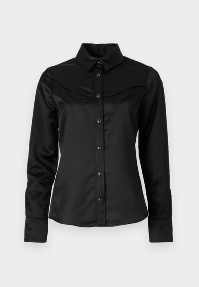 Juodas satino marškiniai su mygtukų uždarymu priekyje, smailiu apykakle ir western tipo pečių siūlėmis su dviem krūtinės kišenėmis. Ilgomis rankovėmis su rankogaliais.