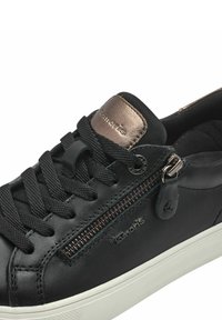 Les sneakers en cuir noir présentent une surface texturée, un accent en bronze au niveau du talon, des lacets ronds et un détail de fermeture éclair sur le côté avec des accessoires en argent.