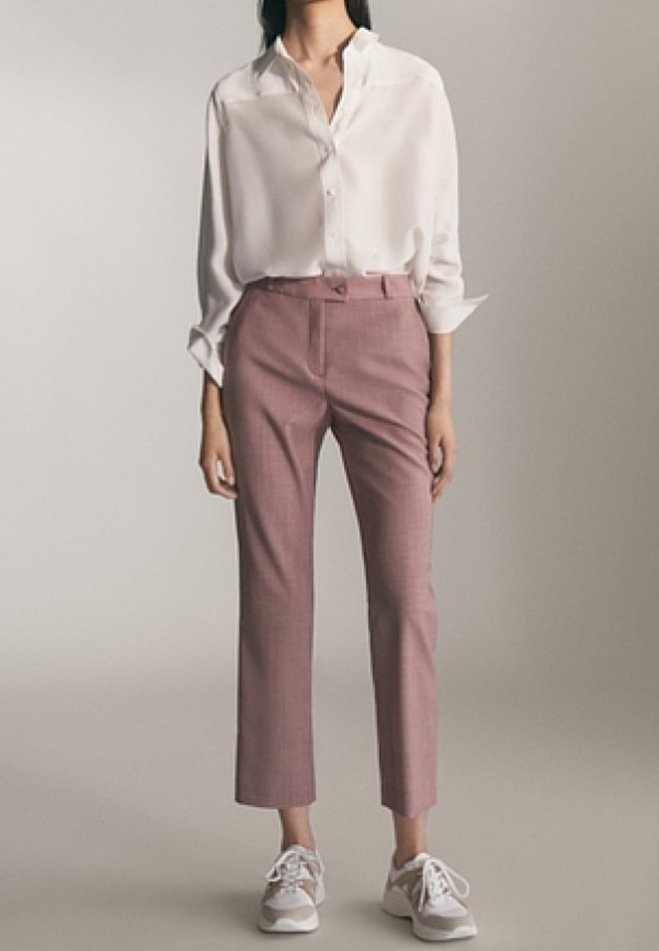 Chemise blanche légère à col, associée à un pantalon rose à carreaux sur mesure et des baskets blanches. La tenue présente une coupe décontractée et une longueur raccourcie.