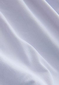 Tissu blanc lisse avec plis doux, présentant une texture fine tissée et des ombres subtiles mettant en valeur son drapé.