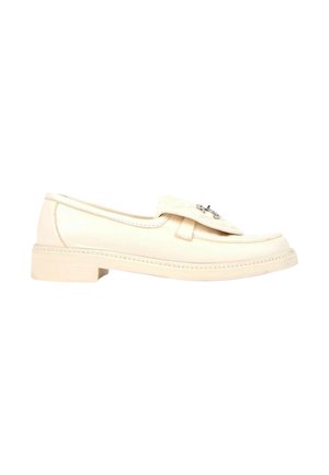 Mocassin en cuir couleur crème avec petit talon superposé et boucle décorative argentée sur le dessus, présenté en profil sur fond blanc.