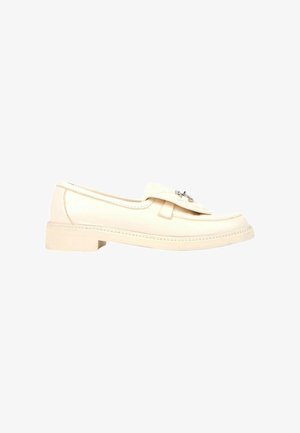 Mocassin en cuir couleur crème avec petit talon superposé et boucle décorative argentée sur le dessus, présenté en profil sur fond blanc.