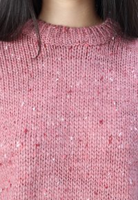 Maglione rosa lavorato a maglia con un motivo a trama, con colletto rotondo a coste e piccole particelle di filo bianco e rosso qua e là.
