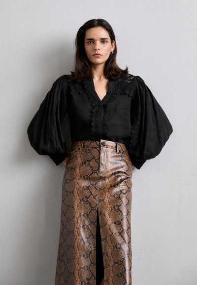Zwarte blouse met getextureerde pofmouwen, gecombineerd met een bruin rokje met slangenhuidpatroon, voorzien van een split aan de voorkant en een glanzende afwerking.