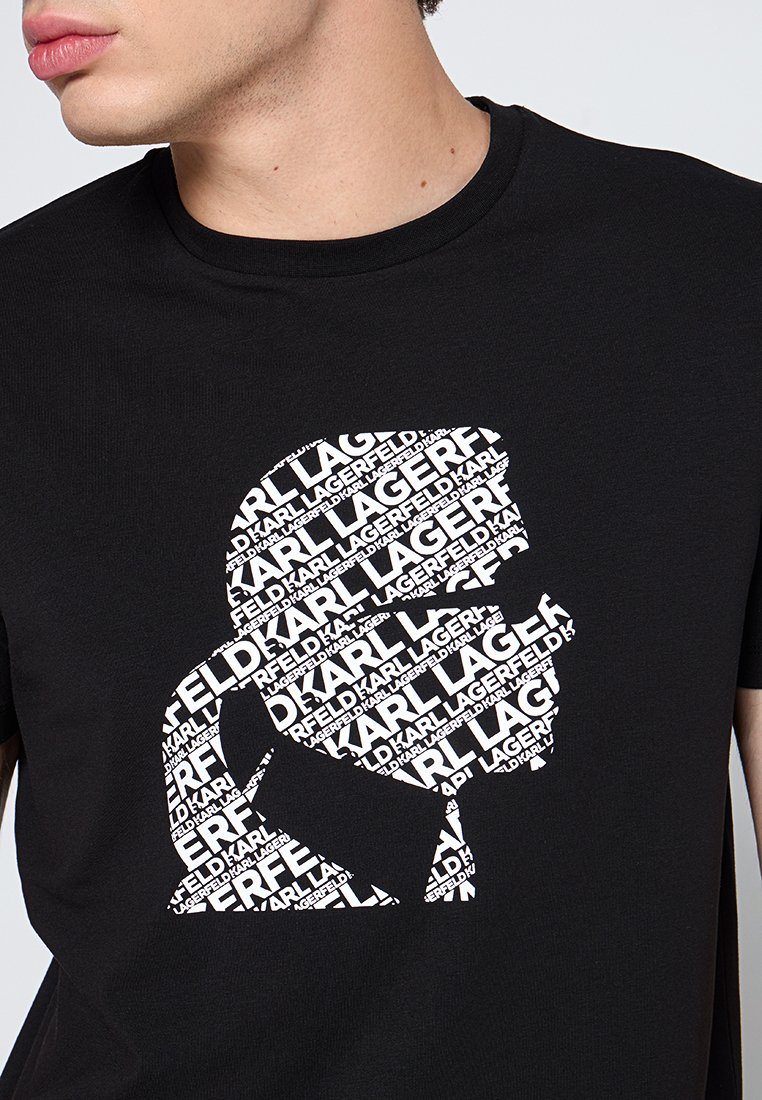 Camiseta negra con un gráfico de texto blanco superpuesto que forma una silueta. Mangas cortas y escote redondeado. Hecha de material de algodón.