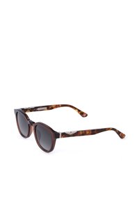 Lunettes de soleil à motif écaille avec des verres foncés et des logos argentés en forme d'ailes sur les branches, inclinées sur un fond blanc.