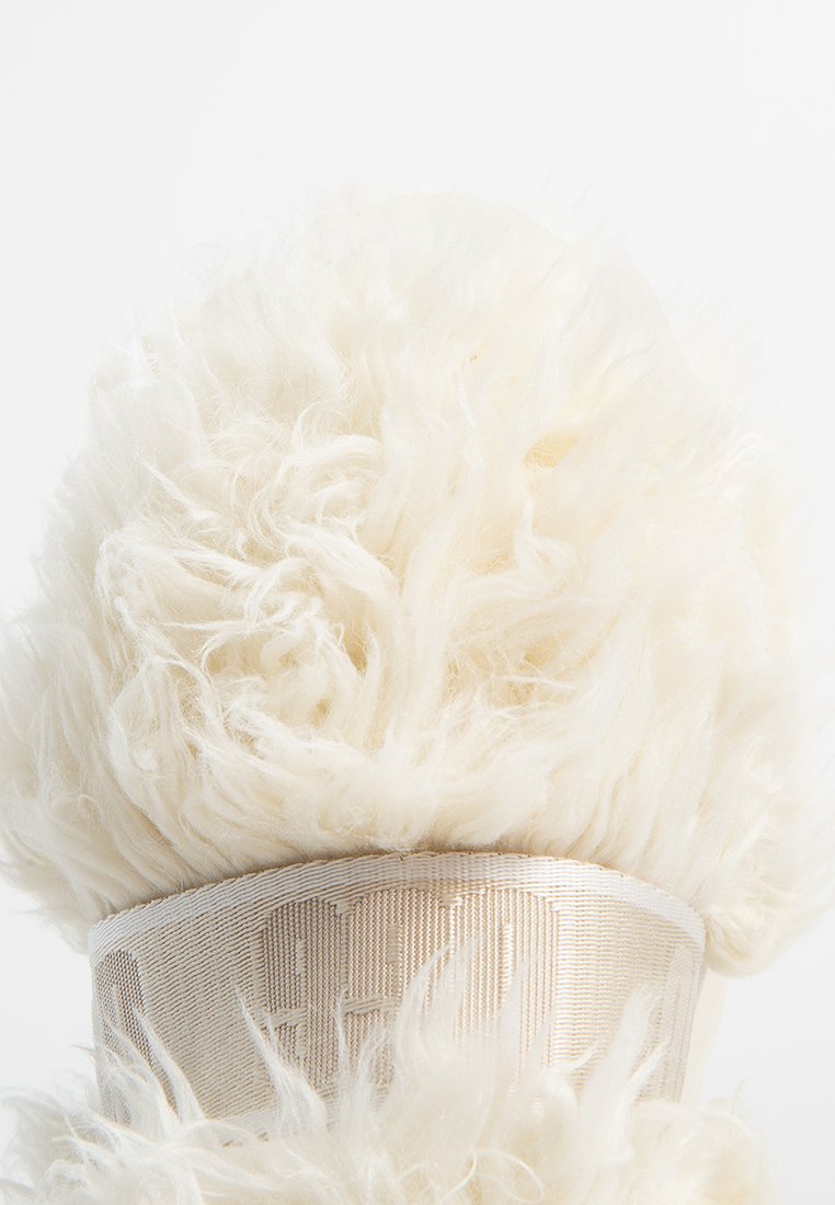 Futrzany, kremowy dodatek o miękkiej fakturze, z szerokim materiałowym paskiem u podstawy z wytłoczonymi literami.