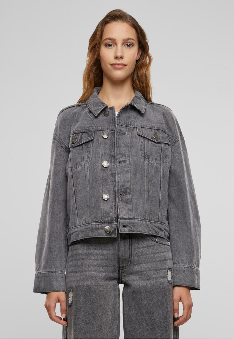 Grå croppad denimjacka med knäppt front, två bröstfickor och en lätt sliten textur. Långa ärmar och klassisk krage.