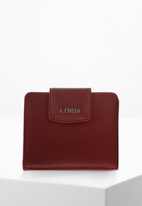 Portefeuille en cuir texturé rouge avec une fermeture à rabat et un logo en argent. Forme carrée, design minimaliste et détails de couture visibles.