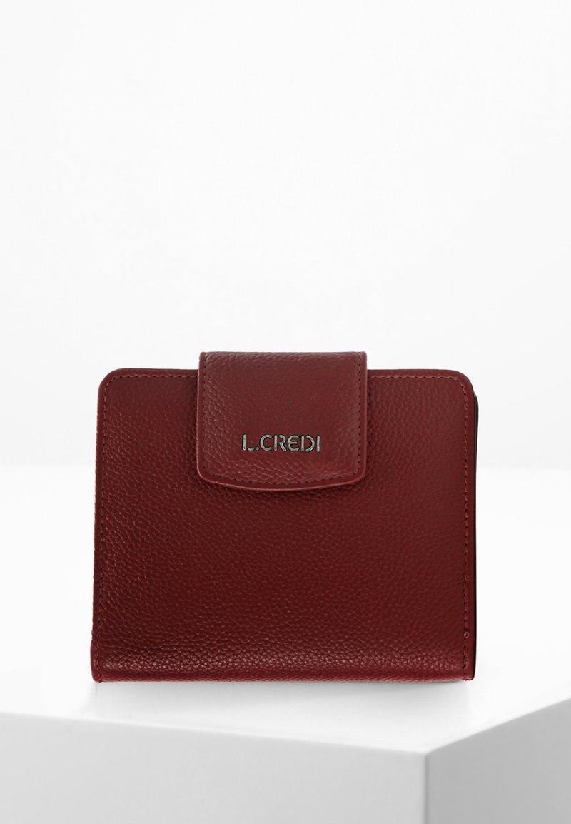 Portefeuille en cuir texturé rouge avec une fermeture à rabat et un logo en argent. Forme carrée, design minimaliste et détails de couture visibles.