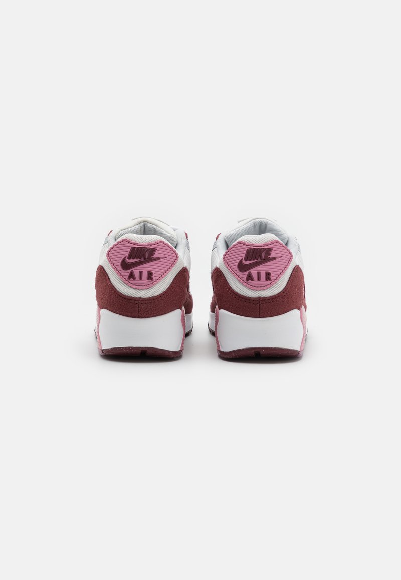 Scarpe da ginnastica bianche e borgogna con una linguetta sul tallone texturizzata di colore rosa che presenta "Nike AIR" in lettere in rilievo. Accenti in morbida pelle scamosciata sulla parte posteriore.
