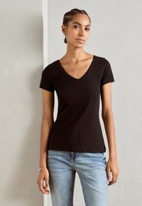 Black short-sleeve V-neck t-shirt made of soft cotton, featuring a fitted silhouette and smooth texture, paired with light blue jeans.
