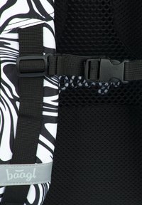 Cinghia dello zaino a righe in bianco e nero con texture in rete, fibbia regolabile e accento del logo grigio. Tessuto resistente con chiusura sicura.
