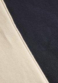 Tissu en coton avec un design à motif en diagonale, comprenant une section beige à gauche et une section bleu marine foncé à droite, surface texturée.