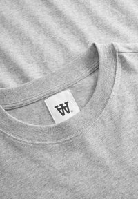 Grå t-shirt lavet af blødt bomuld, med en ribbet runde halsudskæring. Indeholder et hvidt labels med et sort logo indeni kraven.