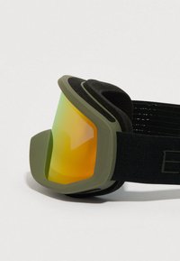 Μάσκα σκι με ελιά πράσινο πλαίσιο, πορτοκαλί ανακλαστικό φακό, μαύρο ρυθμιζόμενο λουράκι και αφρώδη επένδυση για άνεση και ασφαλή εφαρμογή.