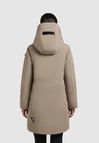 Pufferjack in lichtbeige, met een grote capuchon, een slank ontwerp en zwarte merkaccenten. Geverfde matte afwerking met een knielange snit.
