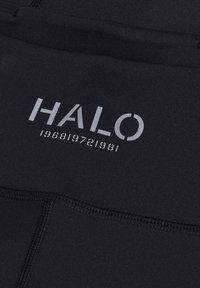 Svart atletisk tyg med slät textur, med "HALO" i silver och ett numeriskt designelement nedanför, som betonar modern stil.