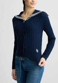 Cardigan a maglia blu navy con colletto da marinaio, caratterizzato da strisce bianche, chiusura con bottoni e motivo a trecce, accentuato da un logo ricamato.