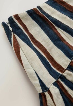 Látka s vertikálními širokými pruhy v námořnické modři, hnědé a béžové barvě, s bílým zipem na levé straně a nabráním blízko spodní části.