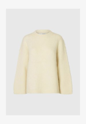 Gaiša krēma krāsa pārāk liela džemperis, kas izgatavots no mīksta, pūkaina materiāla. Tam ir apaļa kakla izgriezums un nolaišas plecu šuves, kā arī ribota aproce un apakša.