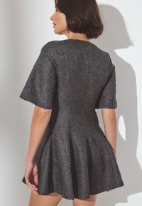 Siva oblečena obleka s kratkimi rokavi, teksturiran material, okroglo izrezovanje in šivani naborki na pasu, ki ustvarjajo tekoč krilo.