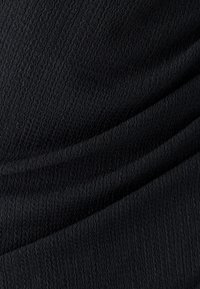 Textured black fabric with visible creases, creating a flowing, layered appearance. Ideal for clothing or upholstery.