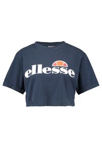Marinblå crop top i bomull med korta rullade ärmar. Har en stor vit "ellesse"-logotyp och en färgglad halvcirkelaccent.
