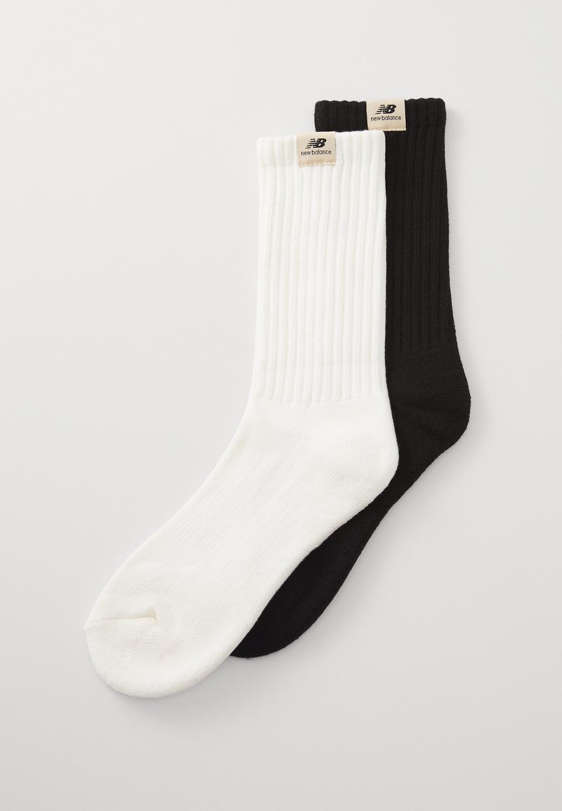 Chaussettes en mélange de coton, côtelées, blanches et noires, avec des accents de logo sur les poignets. Texture lisse, design polyvalent pour un usage quotidien.