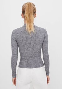 Szary, prążkowany top z długim rękawem, z wysokim kołnierzem i dopasowanym krojem, z ozdobnym, falistym brzegiem i fakturowaną tkaniną.