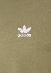 Olivově zelené bavlněné tričko s bílým výšivkovým logem Adidas, které má tři listy a horizontální pruhy. Hladká textura, přiléhavý design.