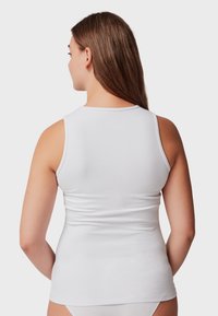 Top sin mangas blanco hecho de un tejido liso y elástico. Diseño ajustado con tirantes anchos y un escote redondeado, con costuras mínimas.