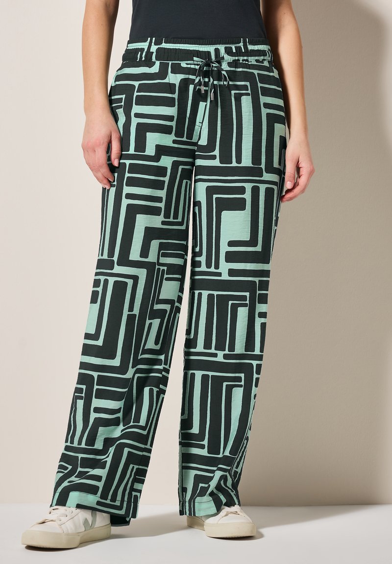 Luźne, jasne miętowe spodnie z czarnym geometrycznym wzorem. Posiadają elastyczny pas i sznurek do regulacji, wykonane z miękkiego, teksturowanego materiału.