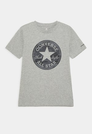 Maglietta a maniche corte grigio chiaro con un grande logo circolare Converse All Star con una stella e del testo al centro.