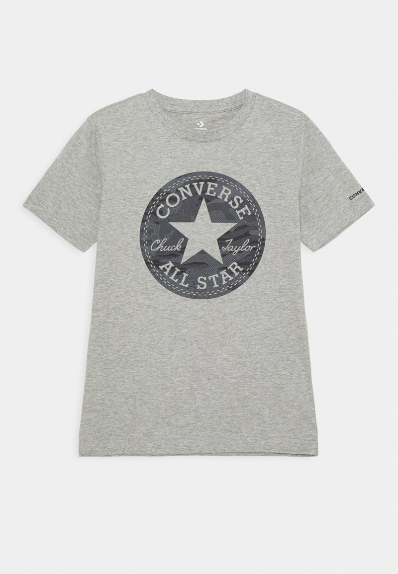 T-shirt gris clair à manches courtes avec un grand logo circulaire Converse All Star comprenant une étoile et un texte au centre.