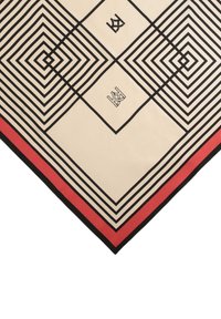 Beige silkkihuivi, jossa on geometrinen musta-valkoinen viivakuosi, jonka reunoilla on punaisia ja mustia korostuksia, muodostaen kolmion muodon.
