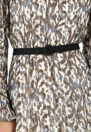 Suurem plaan vööst, millel on must vöö, millel on ümmargune pandlaga pruunis, sinises ja valges mustriga kleidi kohal.