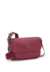 Piccola borsa a tracolla color marrone scuro con chiusura a pattina, tracolla regolabile, tasca frontale e un portachiavi a forma di scimmietta in peluche attaccato.