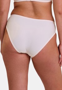 Culotte blanche taille haute avec finitions en dentelle et texture lisse, présentant un design couvrant entièrement sans coutures visibles.