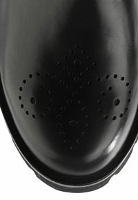 Bout en cuir noir avec un motif perforé décoratif formant une croix symétrique.