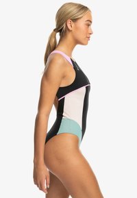 One-piece swimsuit featuring black, pink, and mint sections; sleek design with a high neckline and racerback style. Smooth, stretchy material.