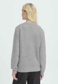 Suéter gris de punto con un patrón texturizado, cuello redondo y mangas largas. El dobladillo y los puños son acanalados, ofreciendo un ajuste relajado.