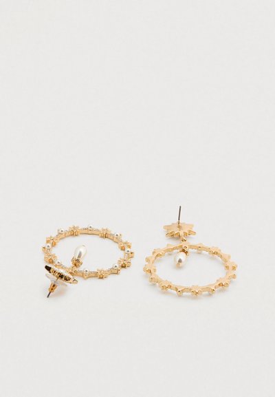 Χρυσά σκουλαρίκια κρίκοι με υφή, διακοσμημένα με μικρές πέρλες και στοιχεία σε σχήμα αστεριού, με κυκλικό σχέδιο και πίσω βάση για καρφί.