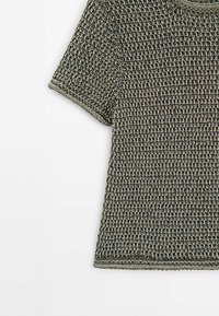 Haut tricoté à manches courtes avec motif texturé dans des tons gris et noirs, présenté sur fond blanc.