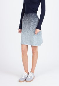 Lichtblauwe rok met een textuurverlooppatroon, met een aansluitende taille, uitlopende vorm en zakken. Gecombineerd met grijze sneakers.