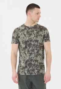 Kortärmad, rundhalsad t-shirt i en mörkgrå bas med ett texturerat, abstrakt mönster i grönt och svart. Tillverkad av lätt och stretchigt tyg.
