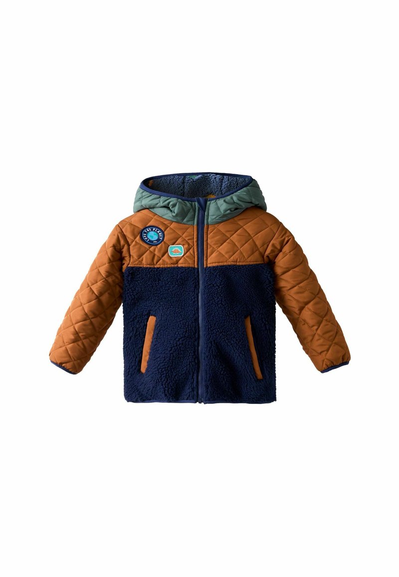 Pūtuvērtā jaka ar brūnu augšdaļu, tumši zilas vilnas ķermeni un zaļu kapuci. Tajā ir divas sānu kabatas un dekoratīvas plāksteri uz krūtīm.